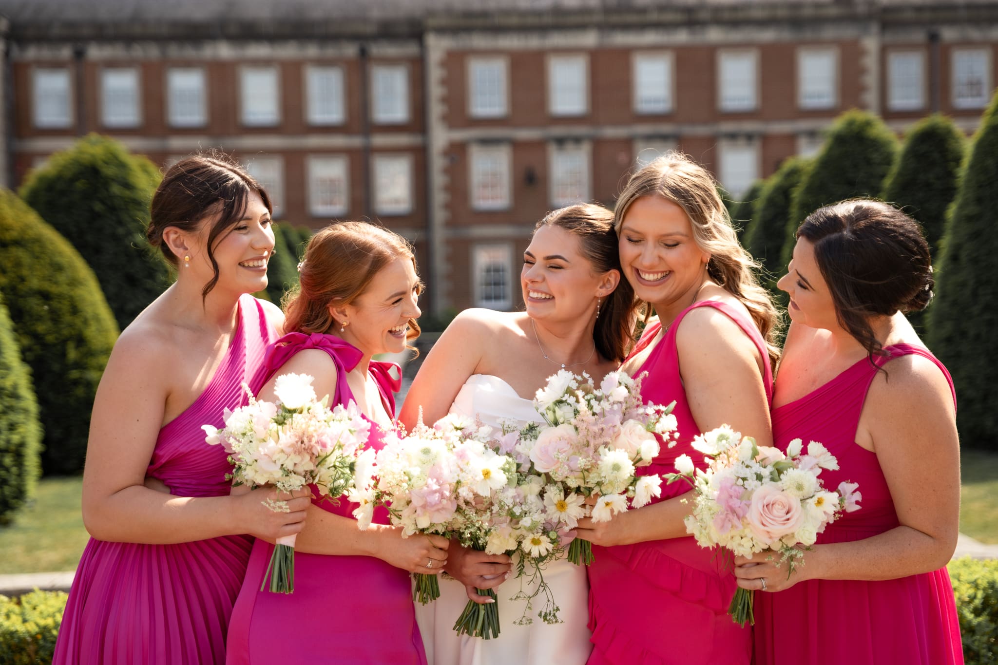 Bride and bridesmaids laughing together in the sunshine at country house wedding | Sussex wedding photographer