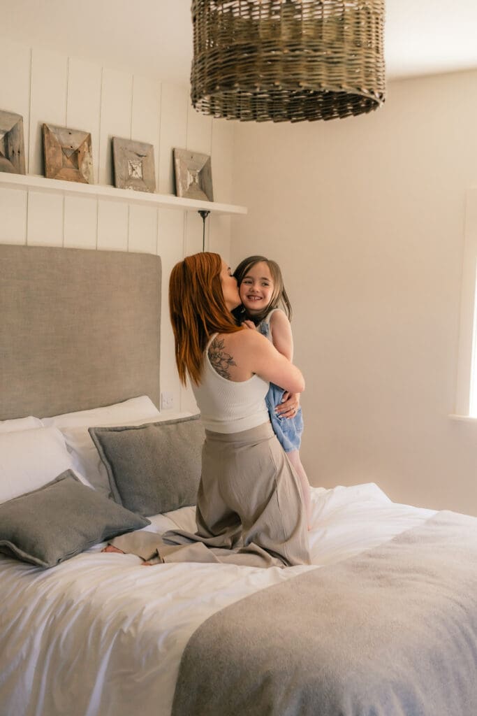 Mother and daughter sharing joyful moment in bedroom Sussex photoshoot