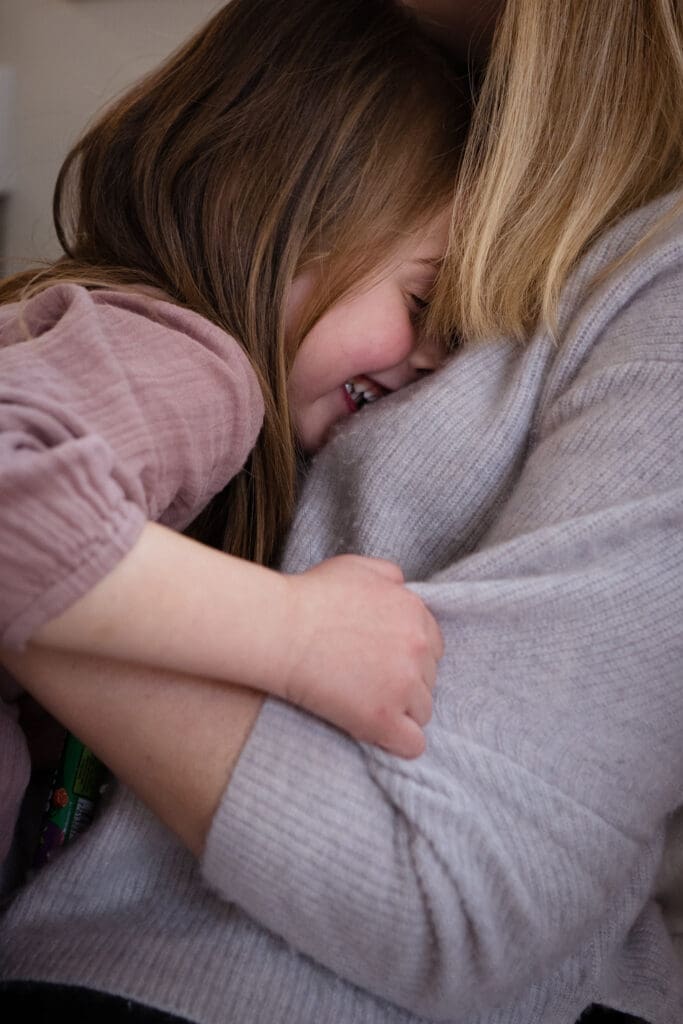 Daughter cuddling mum during natural family photoshoot at home in Sussex