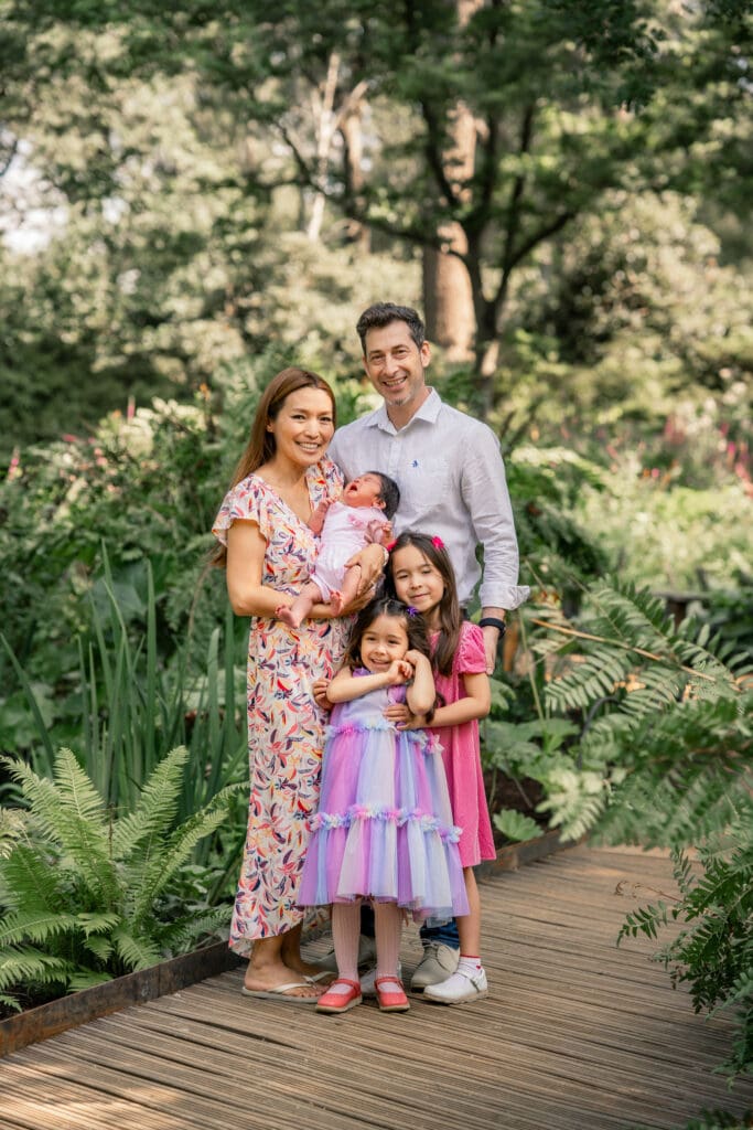 Family walk with siblings and newborn captured in a serene Sussex garden.
