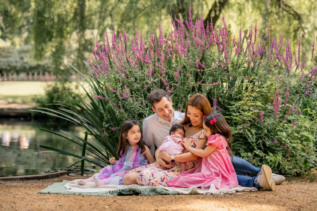 Natural family moment in the park with parents and siblings bonding during newborn photoshoot in Richmond Park.