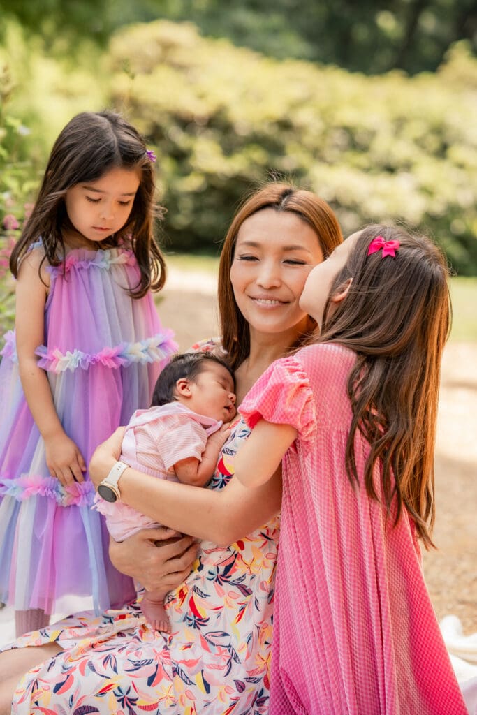 Sweet family moment with siblings and newborn in a peaceful Sussex park.