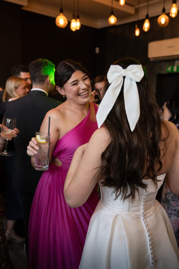 Bride laughing with bridesmaid during wedding reception | relaxed natural wedding photography Sussex