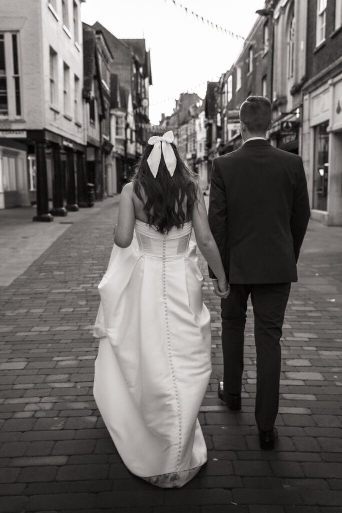 Bride and groom walking hand in hand down cobbled street | romantic wedding photography Sussex