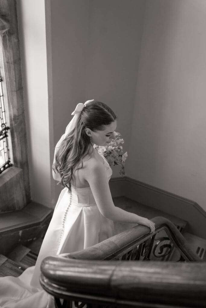 Bride descending staircase with bouquet during wedding morning | natural wedding photographer Sussex