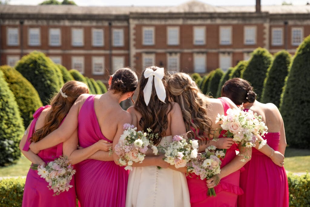 Bride and bridesmaids with bouquets from behind at country house wedding venue | documentary wedding photography Sussex