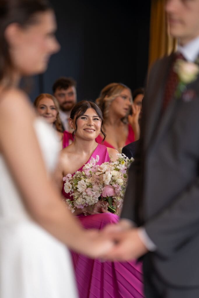 Emotional bridesmaid smiling during wedding ceremony | documentary wedding photographer Sussex
