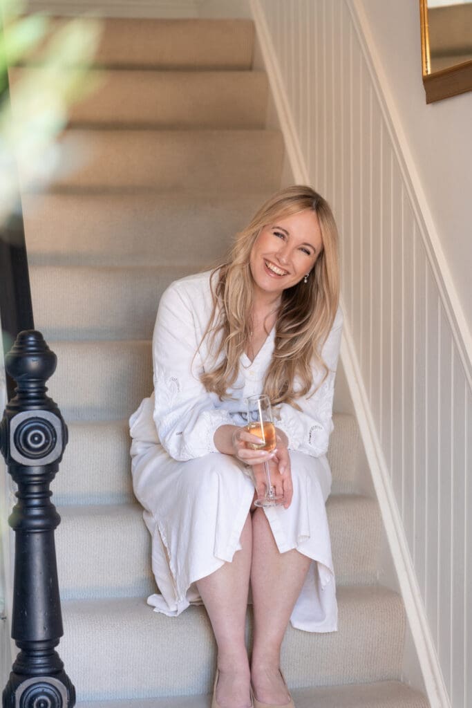Rachel Caws smiling on staircase during relaxed branding photography session at Rustington AirBnB Sussex