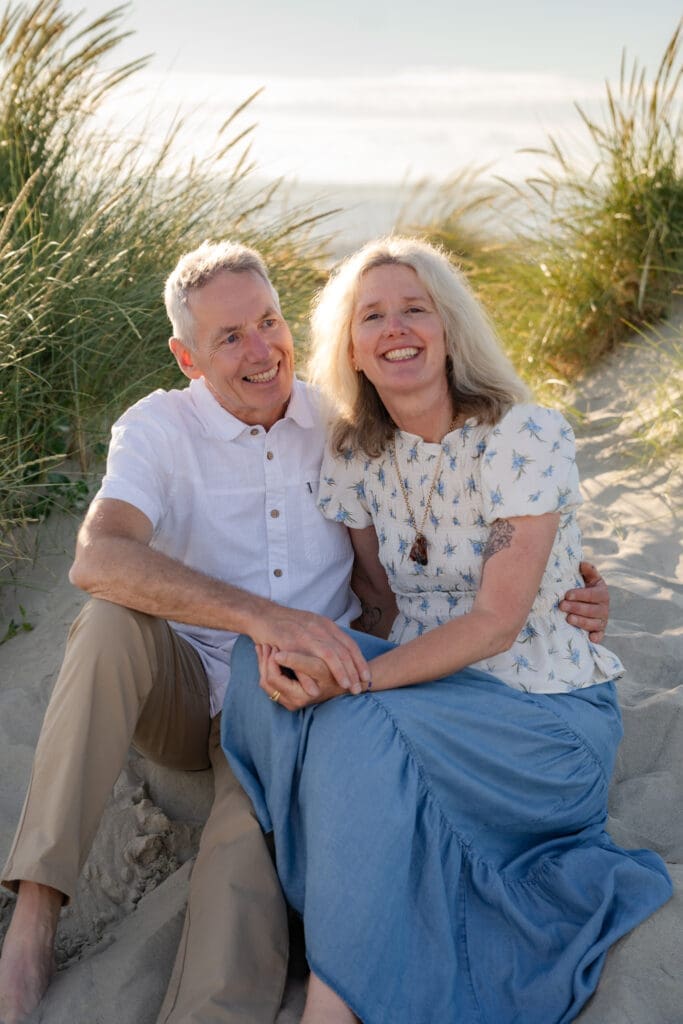 Grandparents embracing in the sand dunes during a golden hour extended family photoshoot in Sussex.
