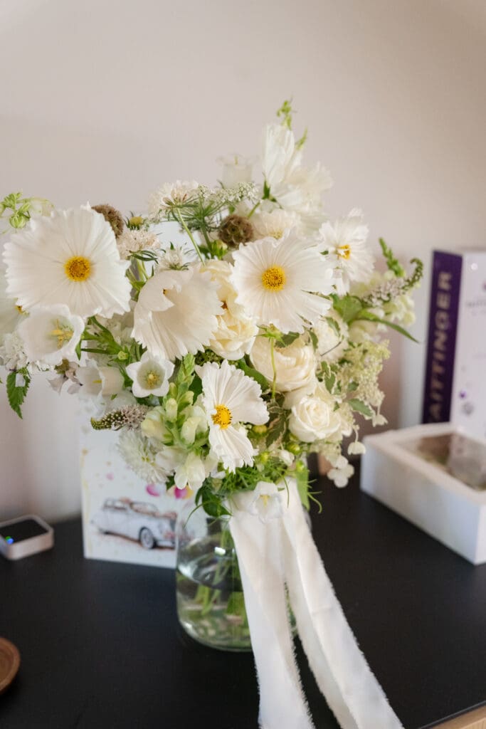 White and cream bridal bouquet of cosmos, roses and snapdragons tied with silk ribbon, photographed on the morning of the wedding