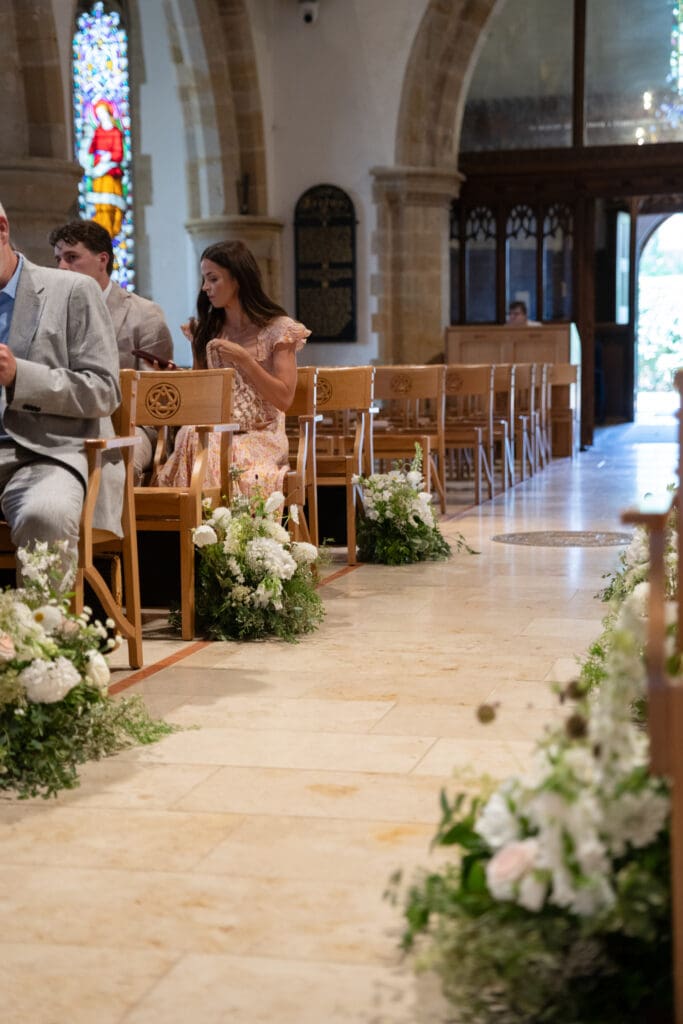 Wildflower aisle arrangements lining the stone floor at Holy Trinity Church, Cuckfield, before the ceremony
