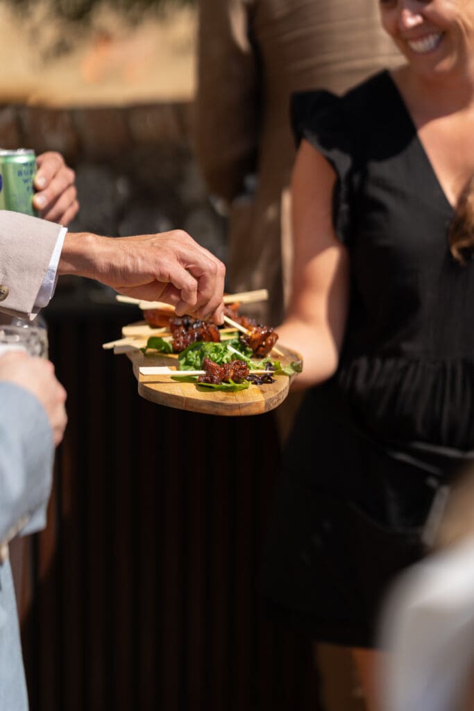 Glazed BBQ canapé skewers served on a wooden board to guests during the drinks reception at Chapel Barn, Sussex