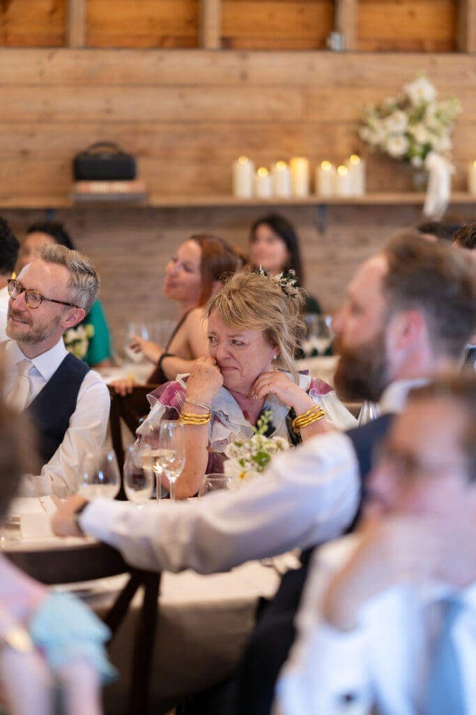 Emotional mother of the groom wiping away a tear during the speeches at the Chapel Barn wedding breakfast, Sussex