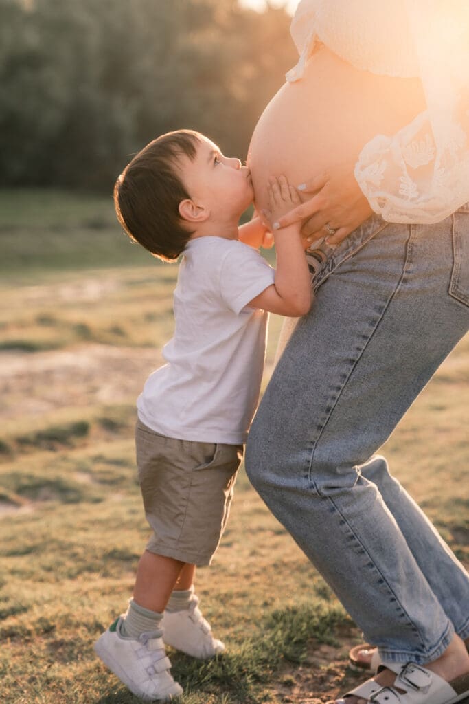 Little boy kissing mum's pregnant belly during maternity photoshoot