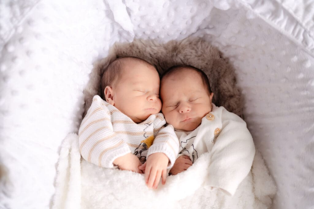 Newborn twins asleep in moses basket during baby photoshoot