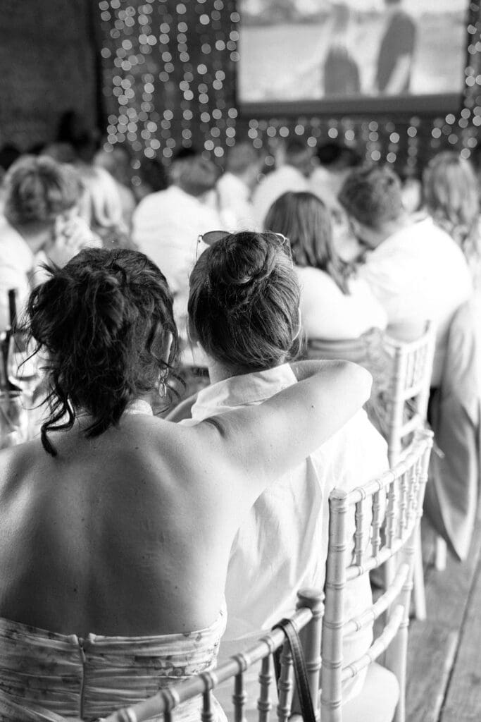 Black and white photo of guest hugging a friend at the table during the wedding breakfast