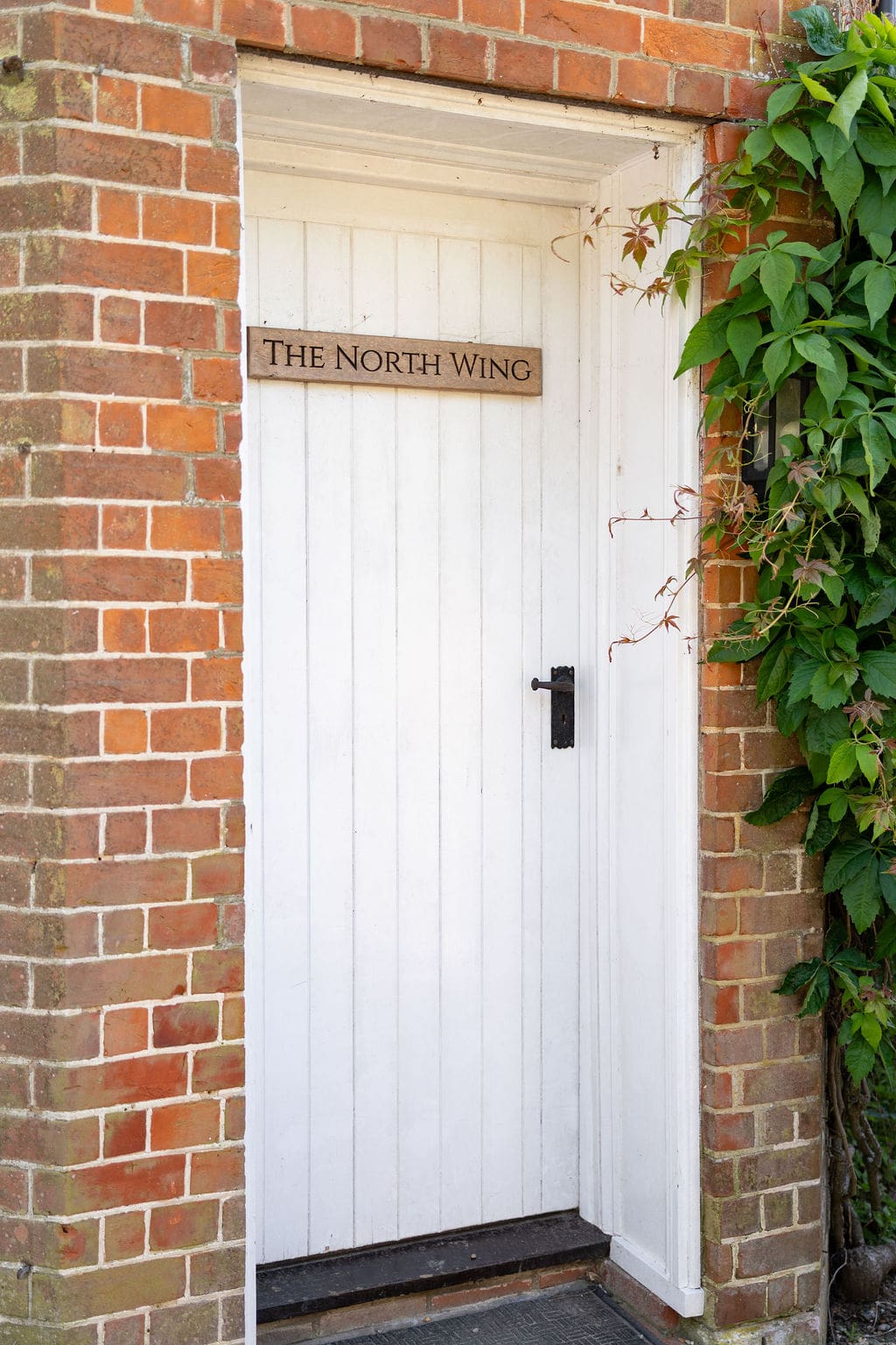 White door with a North Wing sign set in red brickwork at Cissbury House