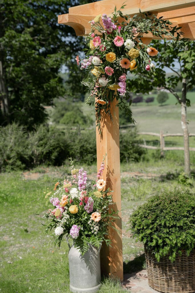 Floral pergola post and milk churn arrangement with fields behind