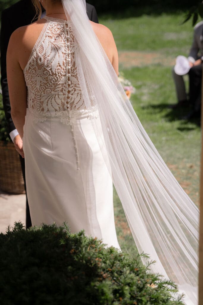 Bride’s lace dress and long veil from behind during the outdoor ceremony at Cissbury Barns