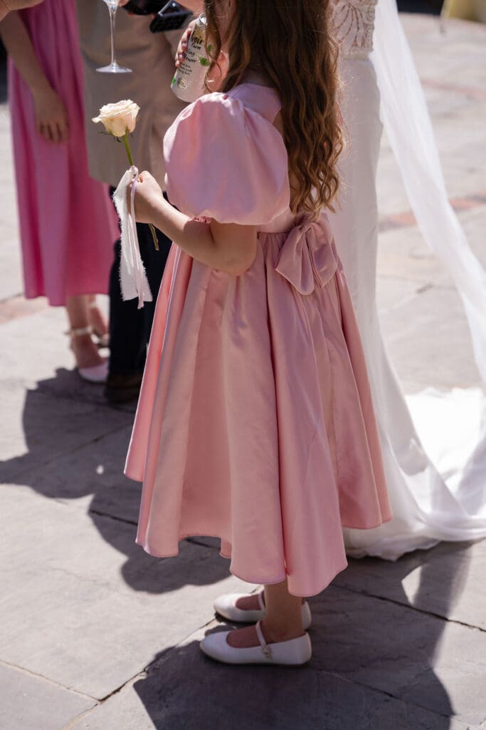 Flower girl in a pink puff-sleeve dress standing beside the bride after the ceremony