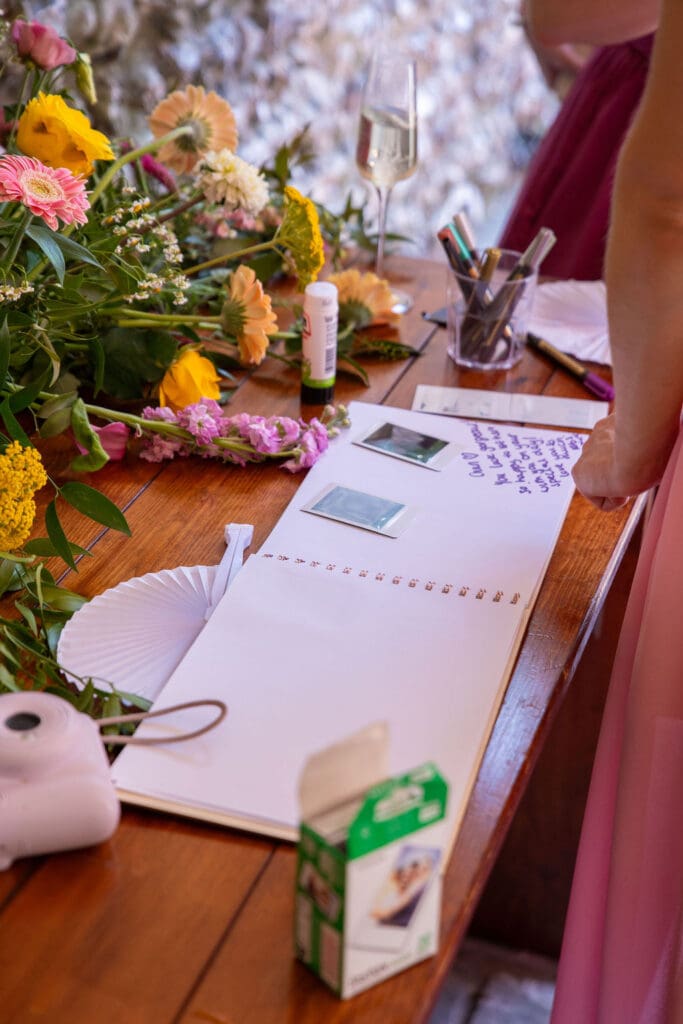 Polaroid guest book and flowers set out on a table for guests