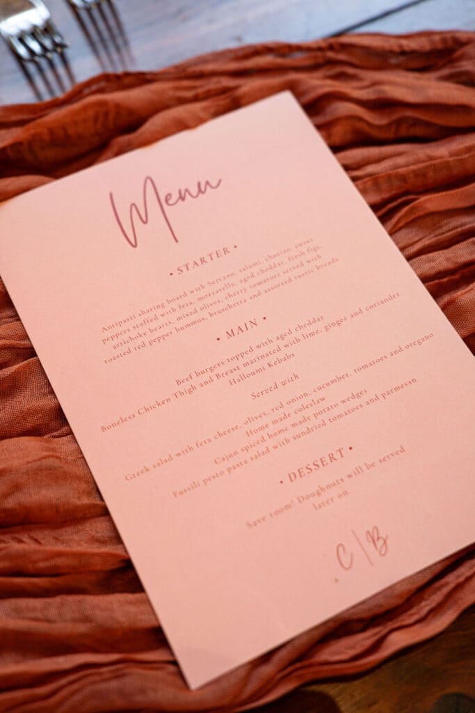 Blush pink menu card on a rust table runner at the wedding breakfast