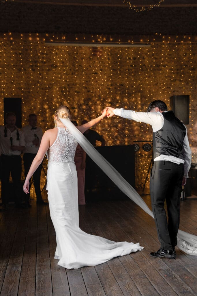 Groom twirling the bride during their first dance, her veil swinging out behind her