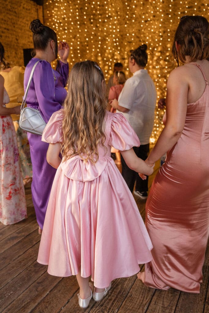 Flower girl dancing with a bridesmaid in the barn