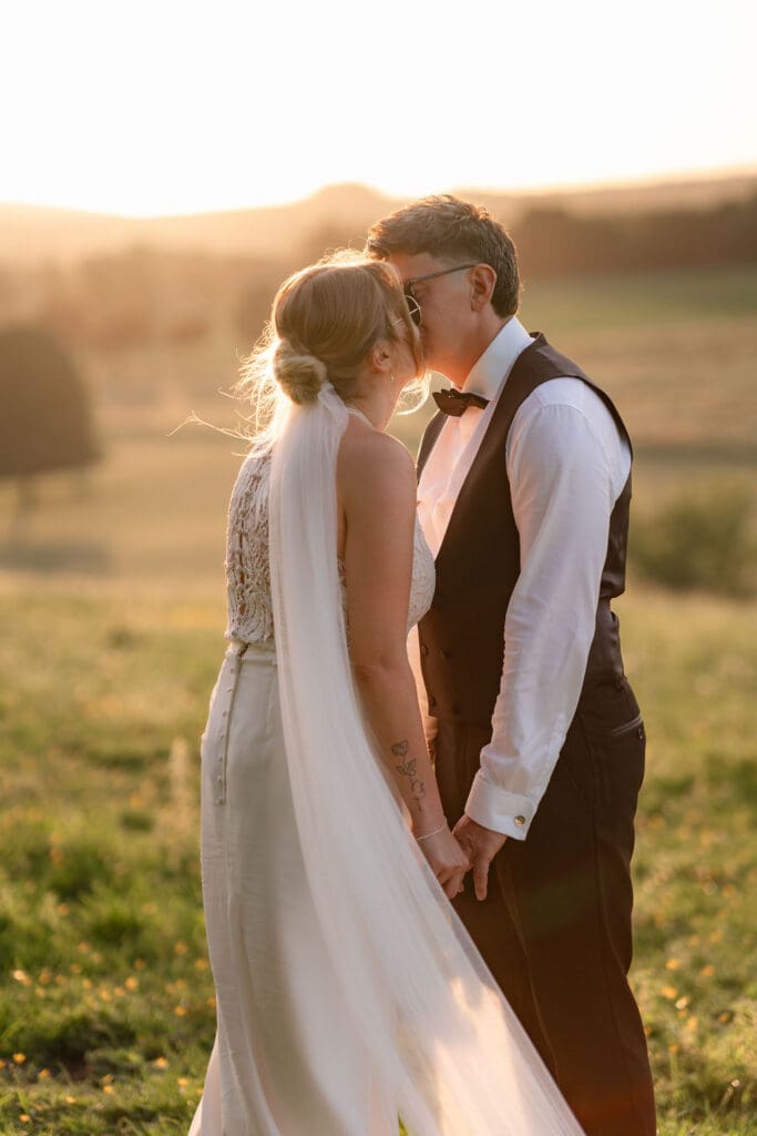 Groom kissing the bride’s forehead in the golden evening light